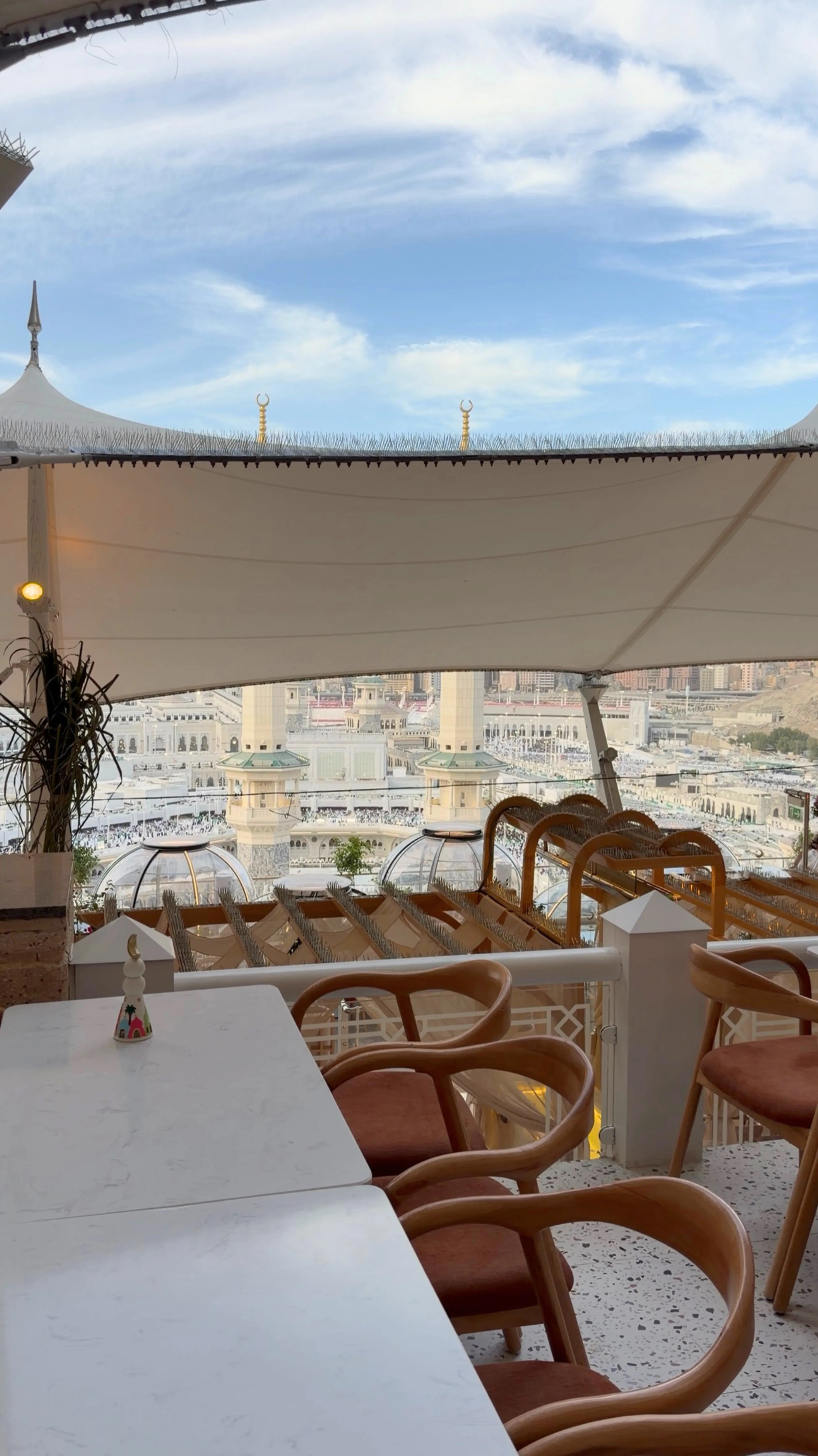 "The outdoor terrace of Mama Ghazail restaurant in Makkah, showing elegant seating under a canopy with traditional mud-style wall designs.