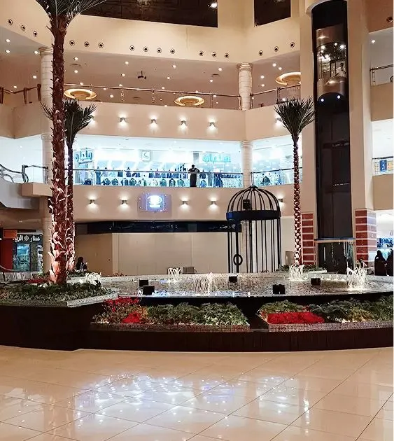 The main atrium of City Center Mall in Makkah with indoor palm trees, a decorative fountain, and multiple shopping floors.