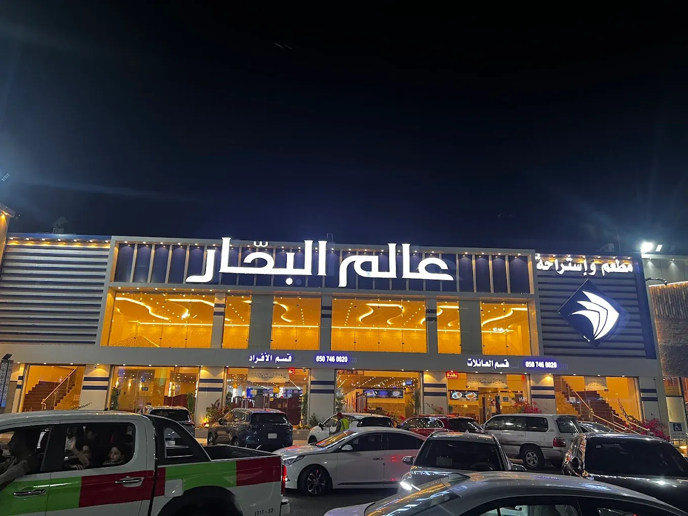 مبنى بإضاءة وسيارات متوقفة أمامه