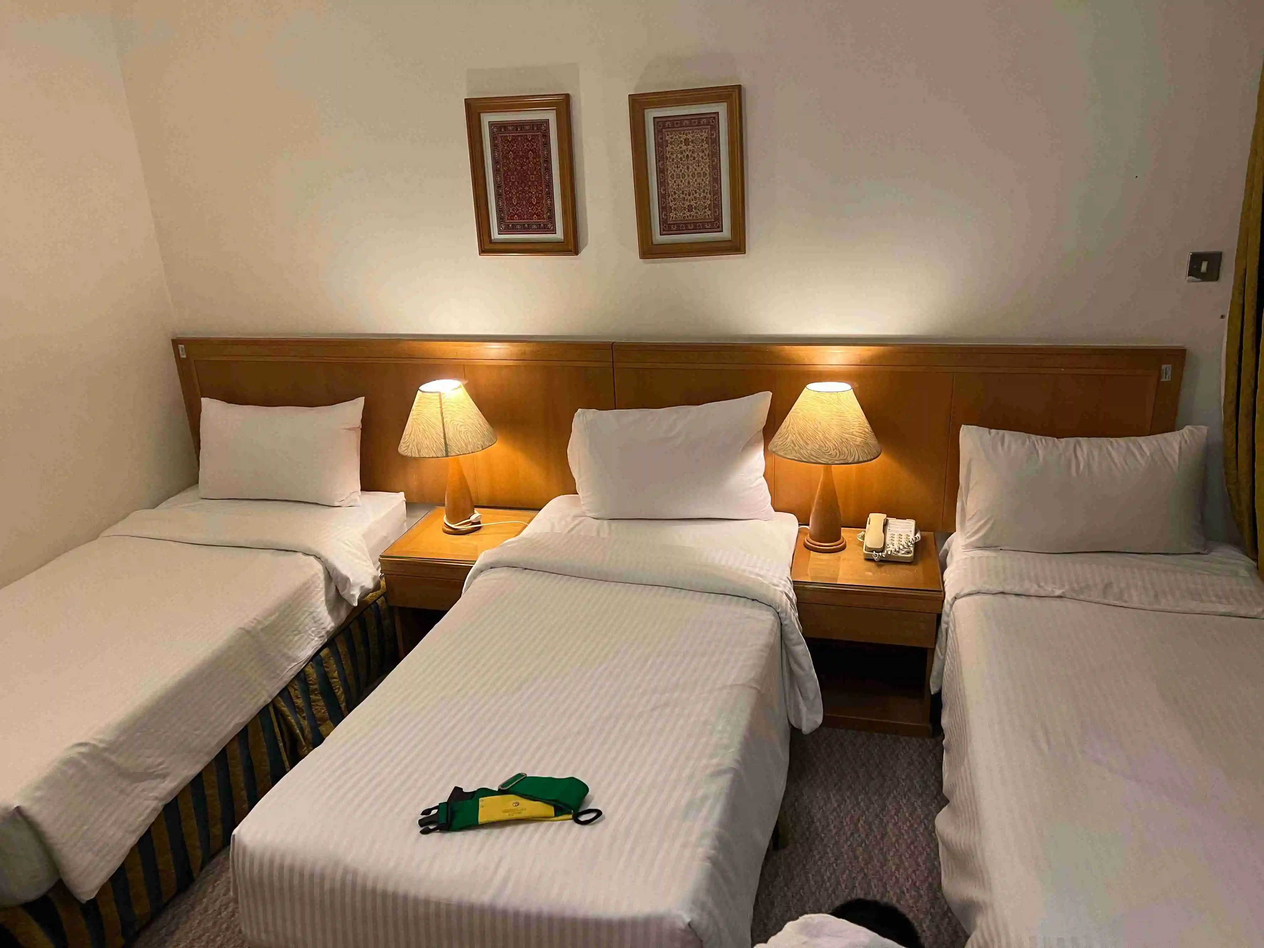 Interior of a hotel room at Elaf Ajyad in Makkah showing three single beds arranged neatly