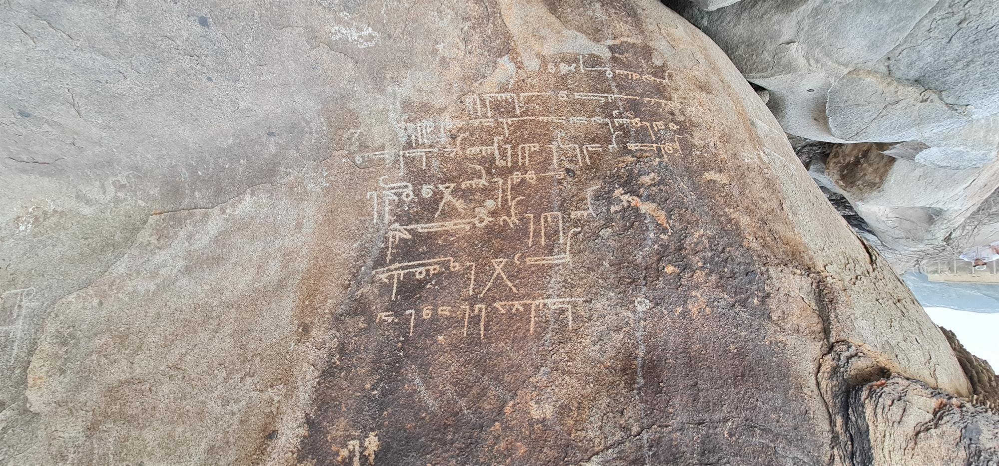 A clear view of long historical Arabic texts engraved on a rock surface in Al-Aseela, Makkah.